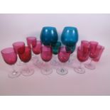 Nine cranberry glass wine glasses with clear stems and feet, 5" high, together with four cranberry