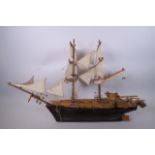 A scratch built treen model of a twin masted sailing ship with four guns, 30" long