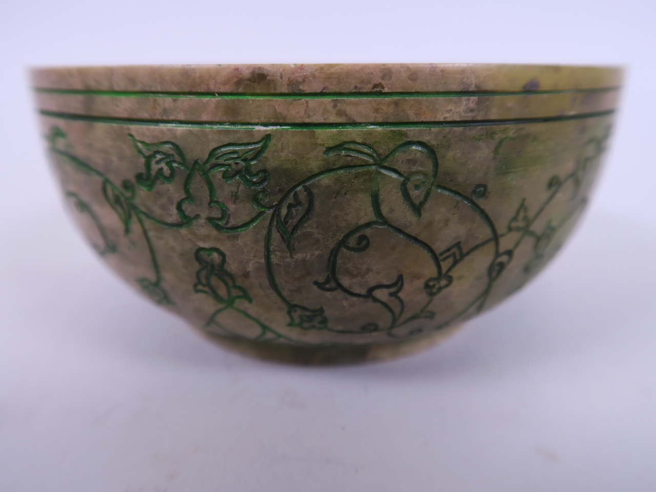 An Islamic soapstone bowl with green highlighted engraved decoration, 4½" diameter (chip to rim)