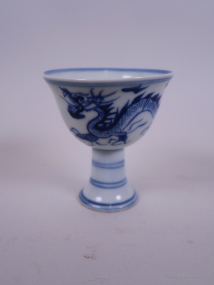 A Chinese blue and white stem cup decorated with a dragon chasing the flaming pearl, 6 character