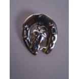 A silver horseshoe brooch, 1" wide