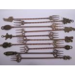 A collection of ten brass toasting forks, the handles cast with various town and country