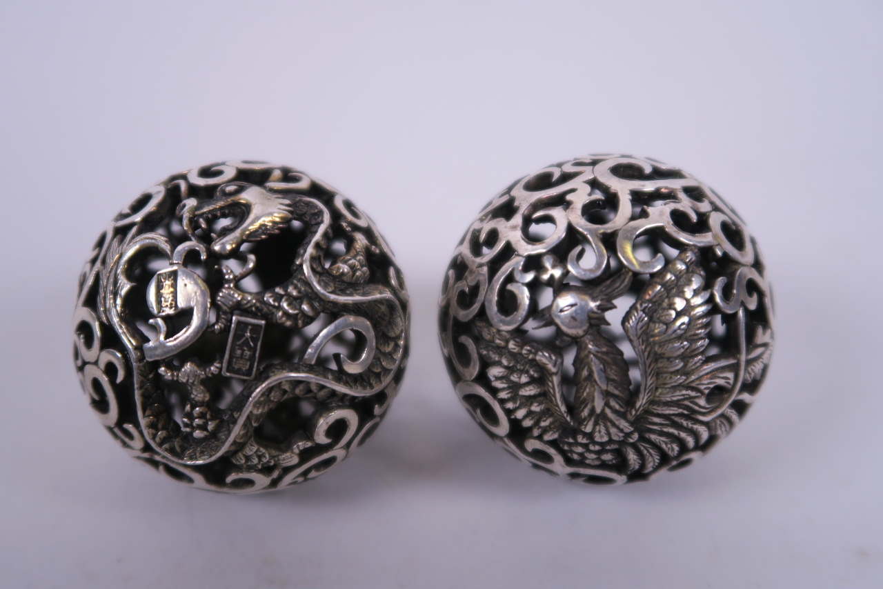 A pair of Chinese white metal meditation balls with pierced dragon and phoenix decoration, 2"