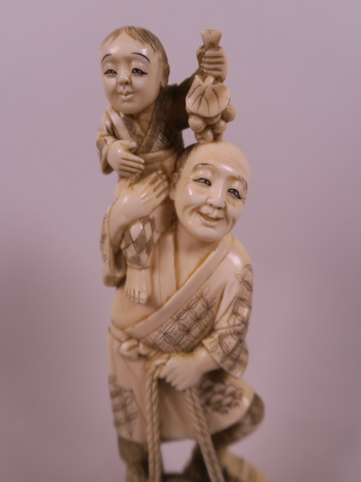 A Japanese carved marine ivory figurine of a farmer with a small child on his shoulder, a basket - Image 3 of 4