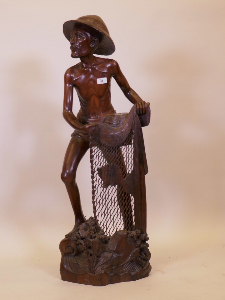 An Indonesian/Balinese carved hardwood figure of a fisherman, signed to base, 40" high