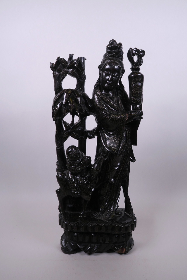 A Chinese carved and ebonised hardwood Quan Yin and child, with inset silver wire decoration, 17½"