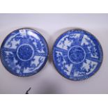 A near pair of Imari blue and white porcelain chargers decorated with panels of flowers and bamboo