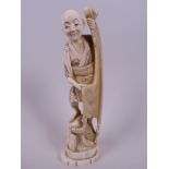 A Japanese carved ivory figurine of a fisherman with net and catch, 7" high