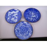 Three Imari blue and white porcelain chargers decorated with landscapes and mythical beasts within