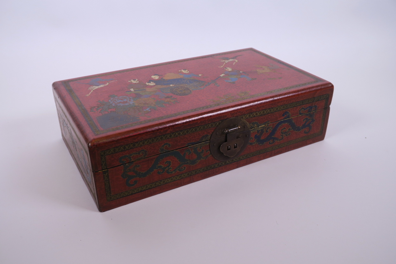 A Chinese red lacquer scribe's box decorated with figures pulling a cart, 13" x 7½"