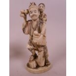 A Japanese carved ivory figurine of a farmer with a child on his shoulder and a basket of vegetables