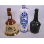 A sealed Delft pottery bottle for Bolls with contents together with a Wade for Bells whisky decanter