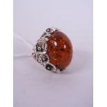 A large silver Art Nouveau style ring set with a faux amber stone, approximate size 'S'