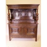 A C18th Welsh oak duodarn, the upper section with carved panel back and turned columns, on a base of