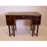 A Continental Empire style knee hole writing table with a leather inset top, raised on fluted