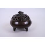 A Chinese bronze censer and lid on tripod feet with pierced bat decoration to lid, impressed mark to