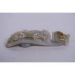 A Chinese celadon jade belt hook carved in the form of a dragon, 4½" long