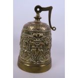 An Oriental brass mission bell with chased face mask and floral decoration, 8" high