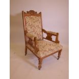 A Victorian satin walnut open armchair with carved crest, raised on turned supports