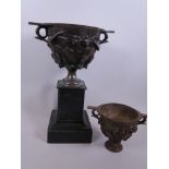 A cast iron metal urn with leaf decoration mounted on a slate plinth, 13" high, together with a