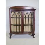 A 1920's mahogany bowfronted two door display cabinet, with astragal glazed doors raised on cabriole