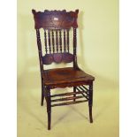 A C19th pressed back side chair with turned and carved spindle back, raised on turned sabre