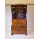 A C18th walnut secretaire display cabinet with glazed upper section over a secretaire drawer with