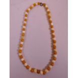 A late C19th/early C20th ivory and butterscotch amber necklace, 19" long, beads 8mm diameter