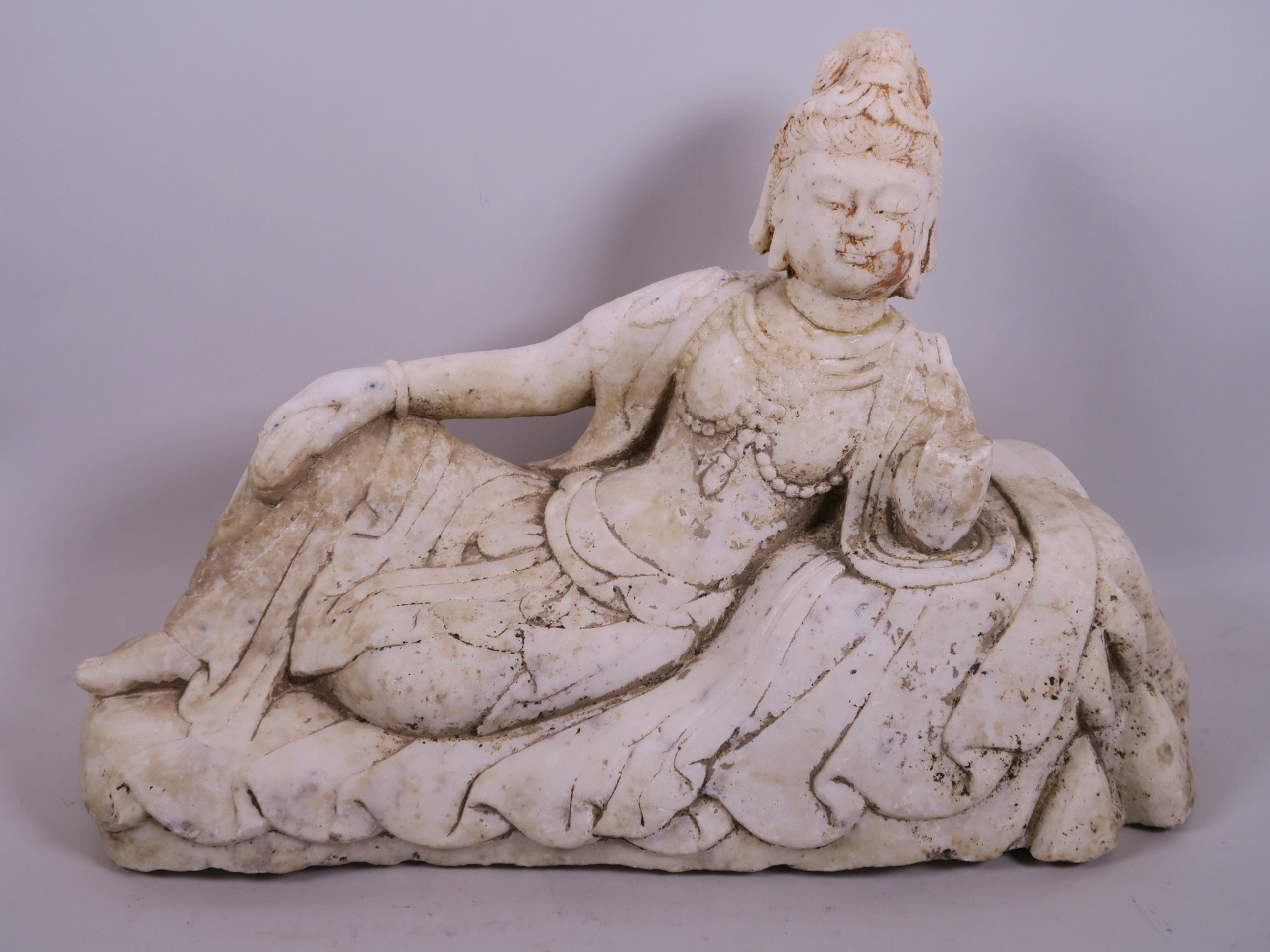 A carved marble figurine of a reclining Quan Yin, A/F, 16" long