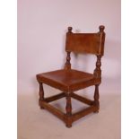 A Spanish colonial walnut monk's chair, with brass studded leather back and seat, raised on turned