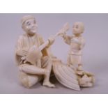 A Japanese carved marine ivory figure group of a seated musician with small child, 4½" high, 5½"