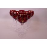 A set of six Bohemian gilt decorated ruby bowl wine glasses on long clear glass twist stems and