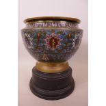 An Oriental champlevé enamelled jardiniere decorated with stylised flowers on a turned wood