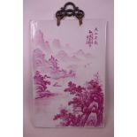 A Chinese porcelain plaque with puce enamel decoration of a riverside landscape with a boatman and