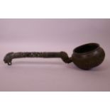 A Sino-Tibetan bronze tea ladle with scrolling decoration and green verdigris patina, 14½" long