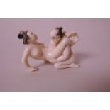 A Japanese Meiji period carved ivory okimono in the form of a couple in an erotic pose, signed, 2"