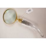 A large hand held brass magnifying glass with a faceted glass handle, 10½" long