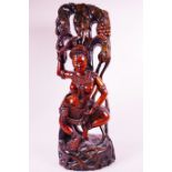 A Balinese hardwood carving of a semi-clad lady by a fruiting tree, 24" high