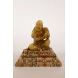 A carved soapstone figure of Shao Lao with a temple dog, mounted on a silk covered stand, Shao Lao