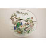 A Chinese famille verte porcelain plaque decorated with women at leisure, 11½" diameter
