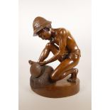 An Indonesian carved hardwood sculpture of a farm worker tying a bale, 16" high