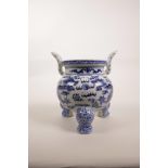 A Chinese blue and white porcelain two handled censer on tripod feet, decorated with dragons chasing