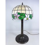 Large Tiffany style table lamp with leaded glass shade on a naturalistic metal base,