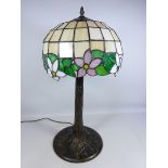 Large Tiffany style table lamp with leaded glass shade on a naturalistic metal base,