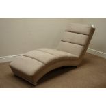 Shaped lounger chair upholstered in neutral fabric,