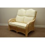 Cane and bamboo two seat sofa with loose cushions upholstered in cream fabric,