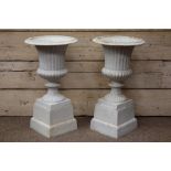 Pair classical style antique finish garden urns on stepped plinths,