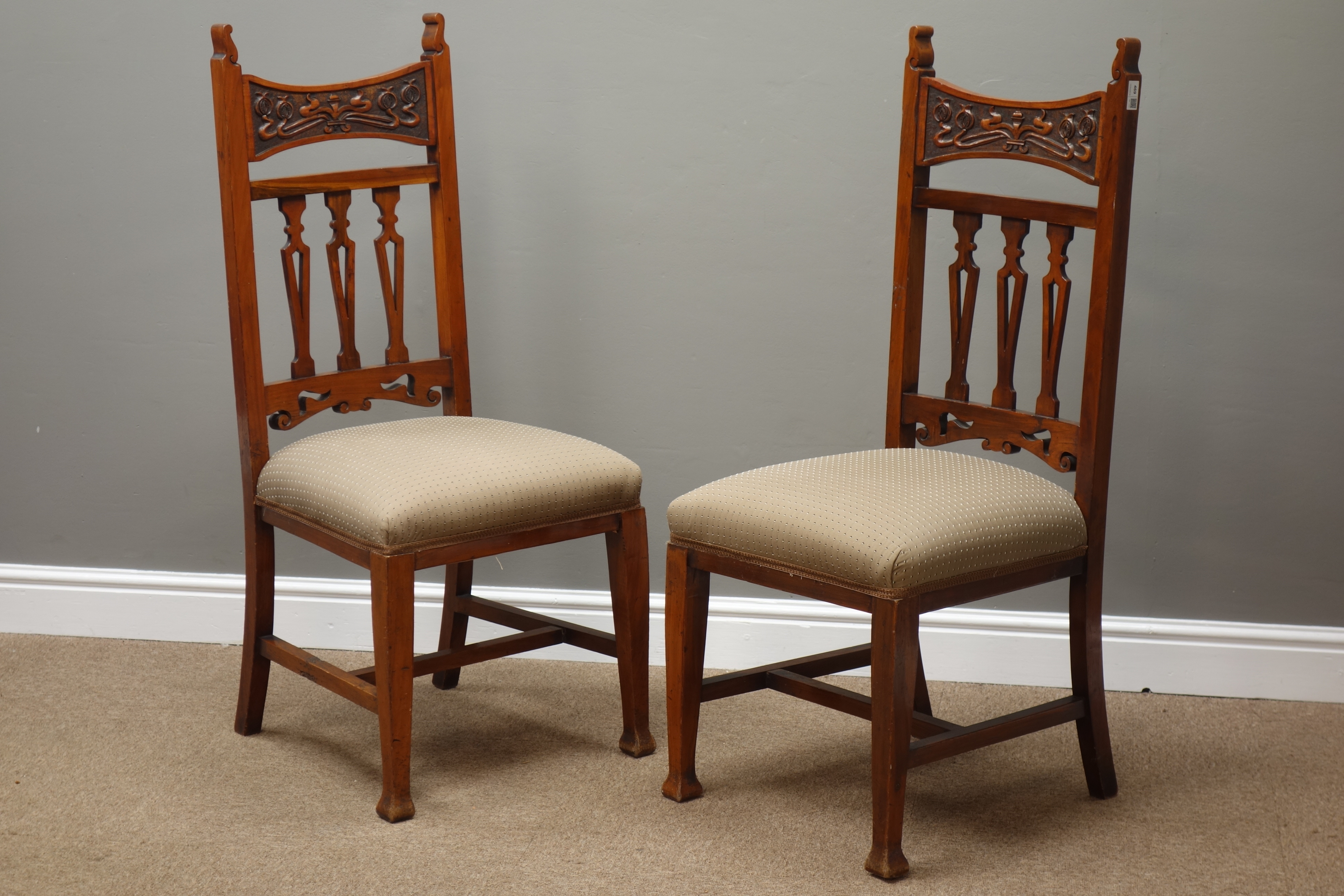 Arts and Crafts walnut framed side chairs, relief carved top rail above three pierced splats,