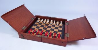 Early 20th century mahogany cased travelling chess set with bone red and white pieces, L25cm x W49.