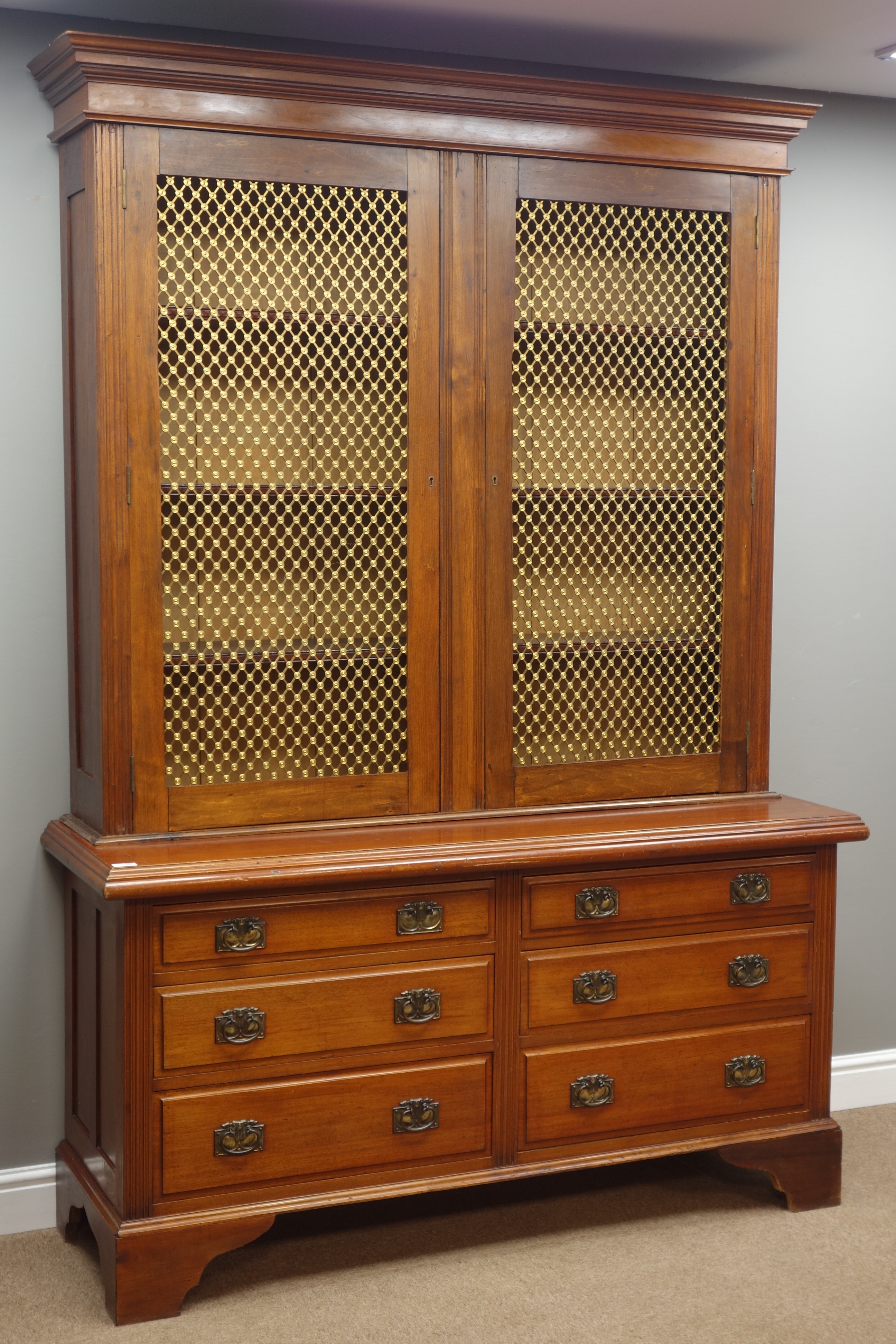 Early 20th century walnut bookcase on chest, enclosed by grille doors, six graduating drawers,
